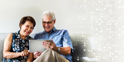 Senior couple using a digital device in a living room