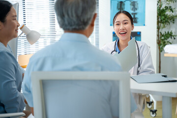 Obraz premium Asian doctor use tablet for results,digital report or health report history online to happy couple elderly patient in hospital.Talking,Medical,healthcare or nurse with advice,support elder concept.