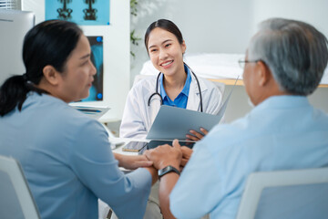 Asian doctor use tablet for results,digital report or health report history online to happy couple elderly patient in hospital.Talking,Medical,healthcare or nurse with advice,support elder concept.