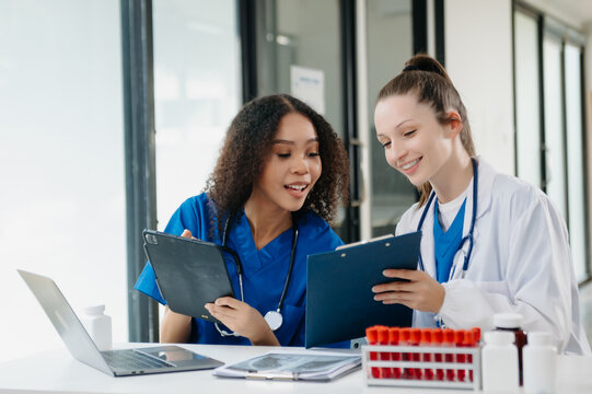 Doctor Talks With Professional Head Nurse or Surgeon, They Use Digital tablet Computer. Diverse Team of Health Care Specialists Discussing Test Result