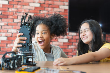 Young Girls Engaged in Robotics and STEM Learning, Diverse Kids Building a Robot Arm in a Science...