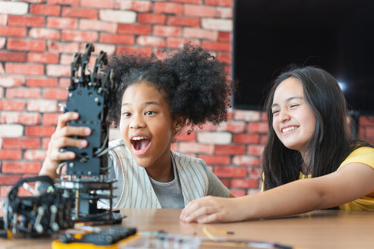 Young Girls Engaged in Robotics and STEM Learning, Diverse Kids Building a Robot Arm in a Science Workshop, Two Girls Exploring Technology and Innovation, Future Engineers