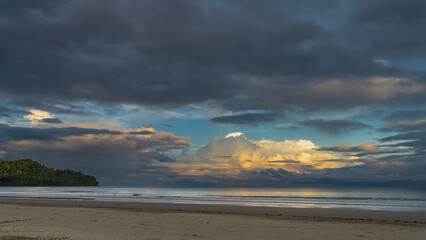 Sunset on a tropical island. The clouds in the blue evening sky are highlighted in gold and pink....