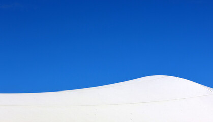White shade sail canopy against a clear blue sky close-up abstract textured background
