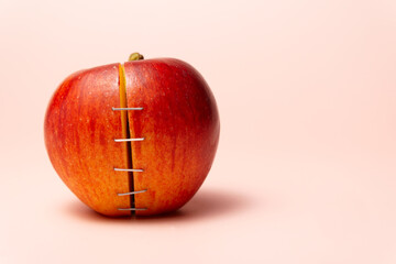 Sliced red apple is held together with staples, symbolizing genetic modification or unhealthy food...