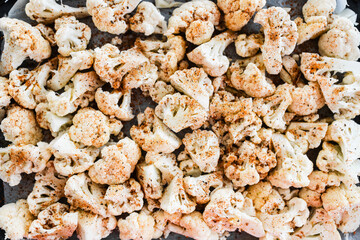 chopped cauliflower with spices on baking tray ready for roasting