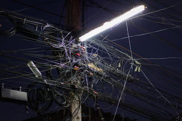 Chaos of cables and wires on an electric pole. Many electrical cable - wire and telephone line on electricity post, Thailand,