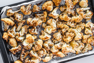chopped cauliflower with spices on baking tray ready after roasting