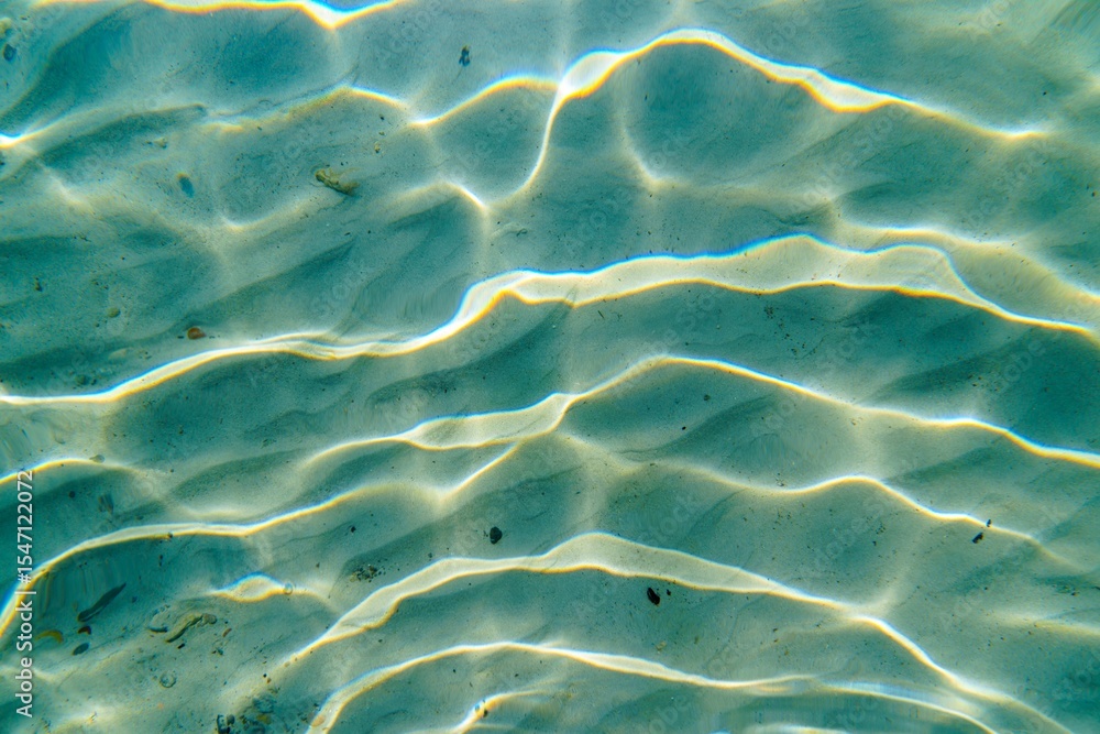 Aufkleber sunlight shines through clear ocean water, creating beautiful patterns of light and shadow on the sa