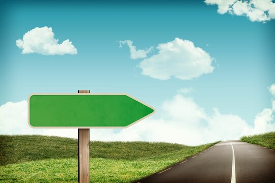 Fototapeta Green directional arrow sign is being shown with road curving through grass hills in flat design