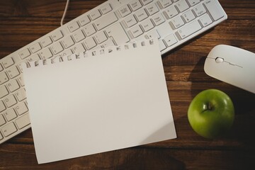 Keyboard with mouse and green apple on table