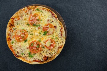 Fresh pizza served on black table