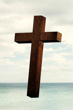 Fototapeta Wooden cross floating over calm turquoise sea under pale cloudy sky in flat design
