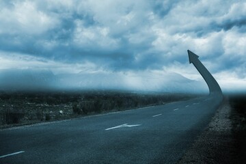 3D render road arrow sculpture is curving upward into stormy sky with misty mountains