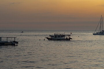 Tranquil ocean seascape featuring various boats under a soft golden hour sky during dusk