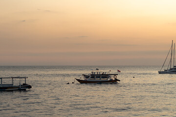 Tranquil ocean seascape featuring various boats under a soft golden hour sky during dusk