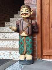 A small wooden welcoming statue of a man in traditional Javanese clothing as a room decoration