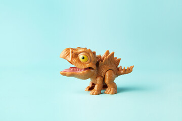 Small and cute plastic stegosaurus toy in action on cyan background © Andi