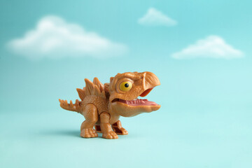 Cute dan mini plastic stegosaurus toy in action on cloudy cyan background
