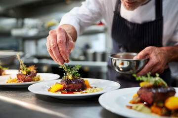 Chef in a restaurant kitchen plating gourmet dishes