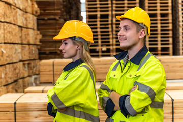 Male and female wood warehouse workers standing arm cross in distribution wood factory