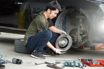 Car brake repairman in the garage,Asian mechanic replaces new brake discs in garage cars.