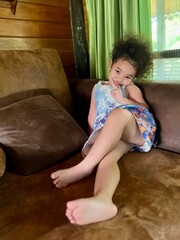 Little girl sitting on the couch in the living room at home.