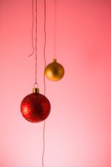 Festive red and gold ornaments hanging against a soft pink background pure holiday magic