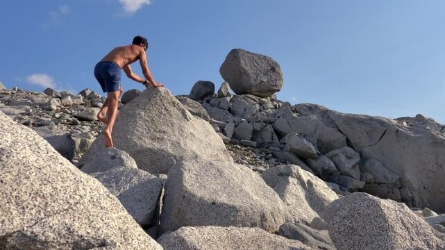 Shirtless Man Climbing Rocky Hill With Large Granite Boulders Along Wendy Thompson Hut Hike In Pemberton, BC. low angle shot
