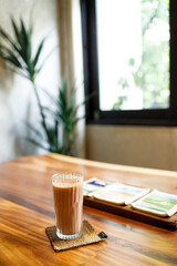Cup of delicious iced chocolate on wooden table background by the window.