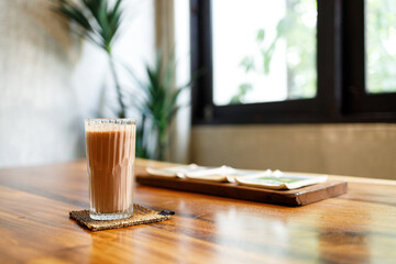 Cup of delicious iced chocolate on wooden table background by the window.