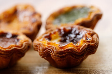 closeup of assorted Portuguese sweet dessert egg tart or Pastel de Nata on wooden board on wooden...
