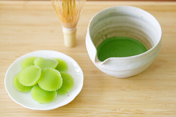 Cup of fresh matcha tea, green tea and Steamed Pandan Layer Cake, Thailand dessert on wooden table.