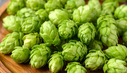 Fototapeta premium Fresh green hop cones on a wooden platter, showcasing their vibrant color and texture, ideal for brewing and beer-making concepts