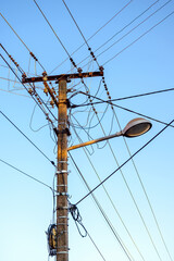 Old wooden lamp post with street light and messy electrical wires