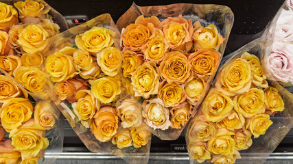 Bouquets of yellow and peach roses wrapped for sale at a flower shop.