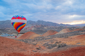Hot air balloon flying over volcanic rock landscape, Colorful Danxia Scenic Area Zhangye City Gansu...