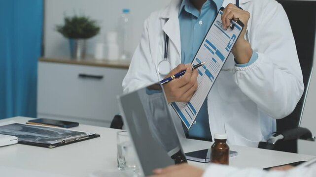 Medical Team Discussing Patient Data with Digital Devices.A group of medical professionals including doctors and a nurse are having a meeting in a bright office. They are reviewing patient information