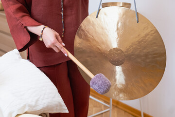 Person relaxing during a sound healing session as a practitioner gently plays a gong. The soothing...