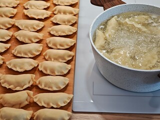 Pierogi ruskie with cottage cheese and potatoes are cooked in a pot