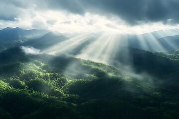 A panoramic view of the Mountains, with rays piercing through the clouds above, surrounded by lush greenery and forest-covered hills below. 