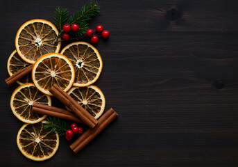Naklejka premium Dried orange slices and cinnamon on dark wood