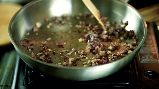 Chopped red onions and garlic in a pan with wooden spoon