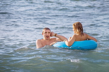 A young couple swims in the sea with an inflatable circle