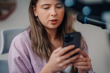 Content creator recording podcast and reading from smartphone