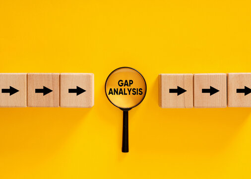 Magnifying glass focusing on gap analysis between two sets of wooden blocks with arrows pointing right
