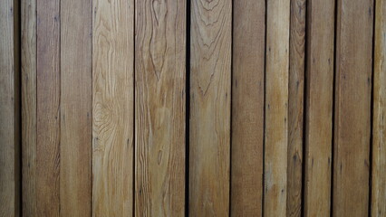 Naklejka premium Wooden fence, background of the wall made of wooden texture. Background with wooden beams. Interior of a village wooden house with vertical logs. Texture of tree trunks of different widths