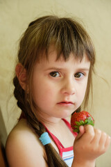 Joyful Child Savoring a Fresh Strawberry. Close-up portrait captures a young girl with braids delightfully biting into a ripe, juicy strawberry, embodying healthy eating and childhood joy.