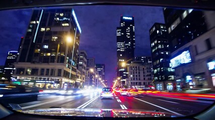 Night cityscape from car dashboard with motion blur light trails on busy street, modern urban lifestyle, high speed driving, city lights, transportation, technology, downtown commute, nightlife