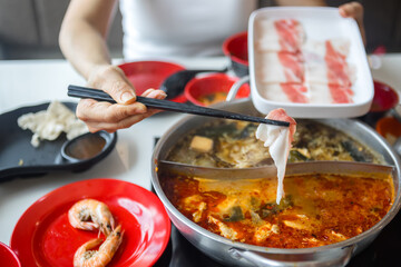 Close-up of a woman putting food in a shabu-shabu pot